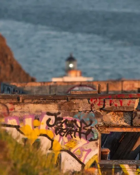 A harbor with graffiti in the foreground and a lighthouse beyond