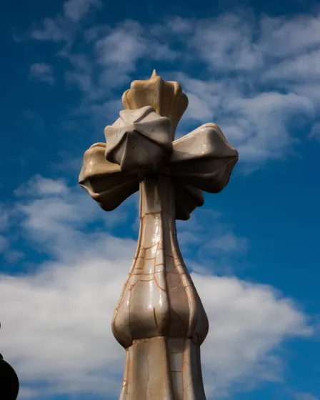 A stone cross against a blue sky with clouds