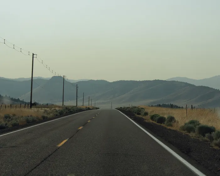 An empty two-lane road running toward distant hills