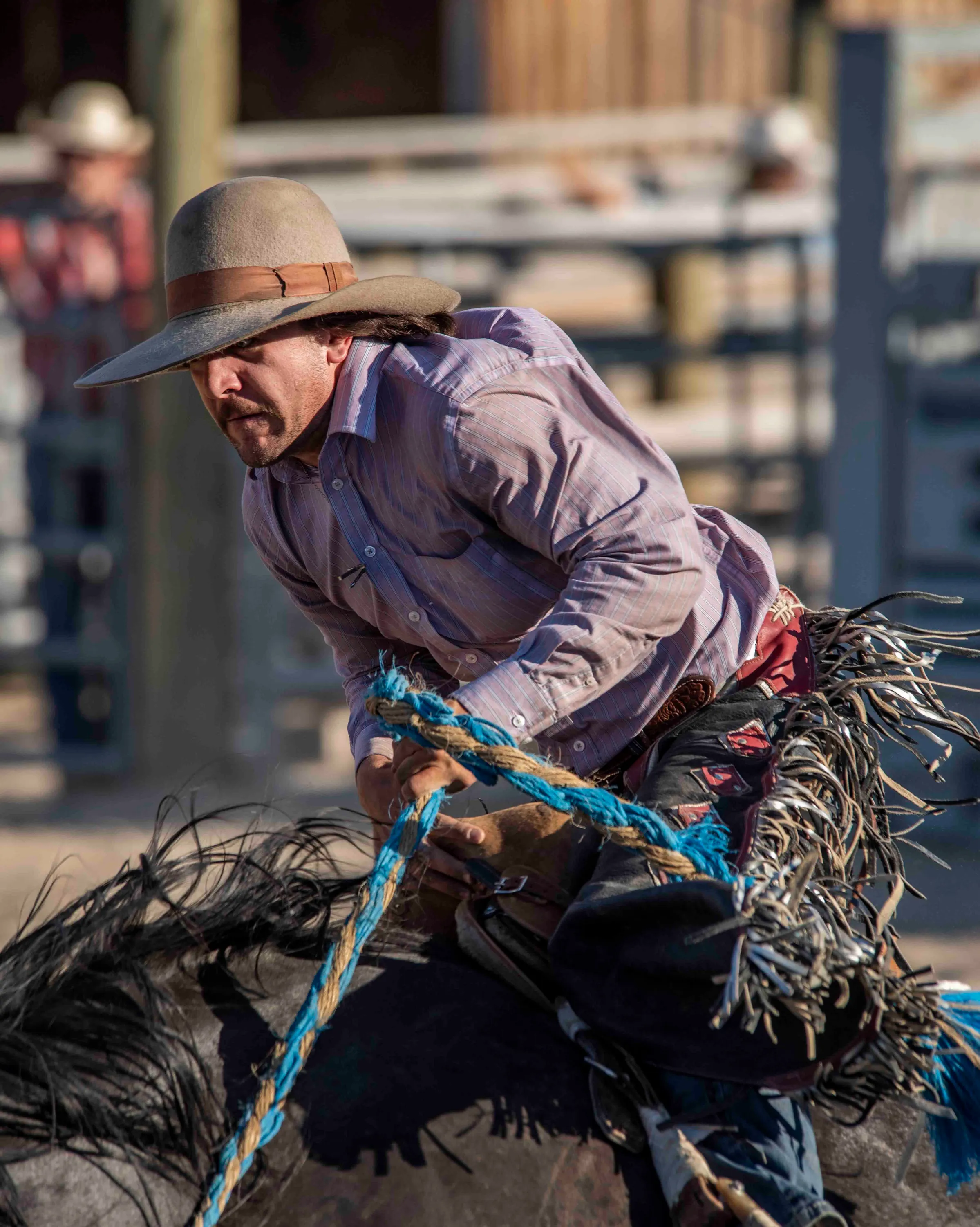 A rodeo rider gripping the reins of a bucking horse