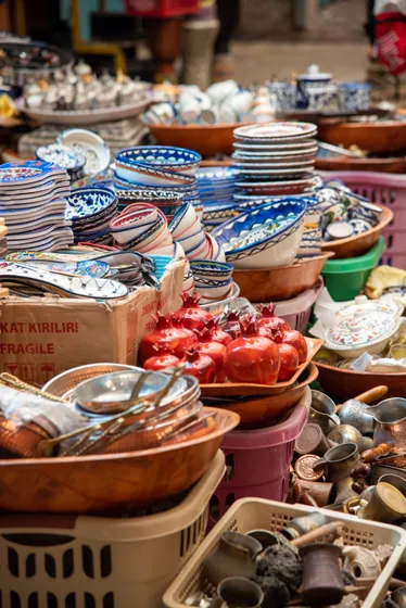 A market stall stacked with painted ceramic bowls and pomegranates